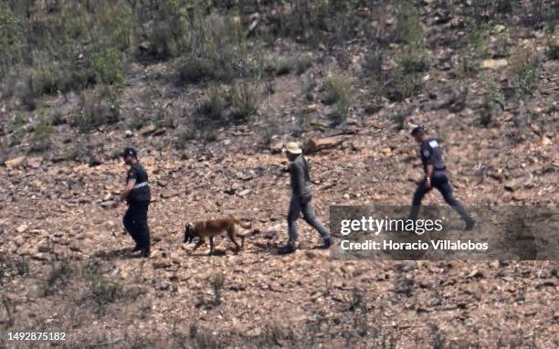 German and Portuguese Judiciary police members, seen through heat haze, walk with a sniffer dog to the search area by the waterline for remains of...