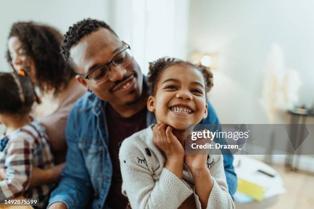 famille multiraciale avec deux filles à la maison. père jouant et riant avec sa fille aînée - un jour comme les autres images en série photos et images de collection