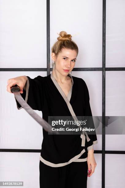 attractive girl in kimono and hair sticks against white background holds katana sword - ninja sword stock pictures, royalty-free photos & images