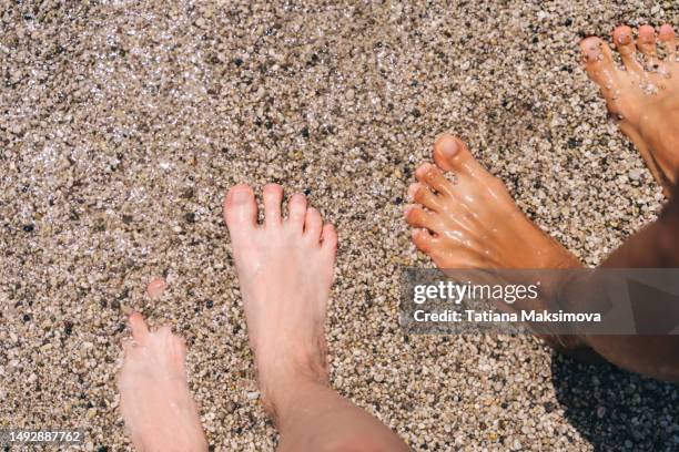 tanned feet next to white feet on small pebbles, top view. - female feet at spa stock-fotos und bilder