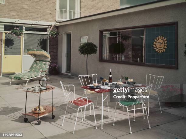 Exterior view of metal garden chairs and a table set for lunch for four people on the patio of a modern detached house in the town of Kidderminster...