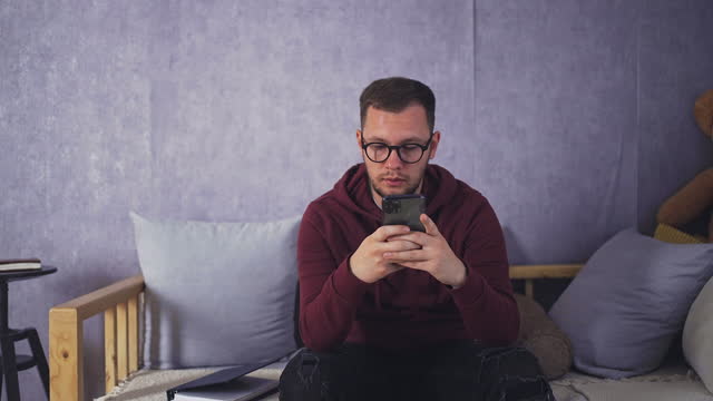 Relaxed Student Messaging Friends with Phone in Comfortable Living Room