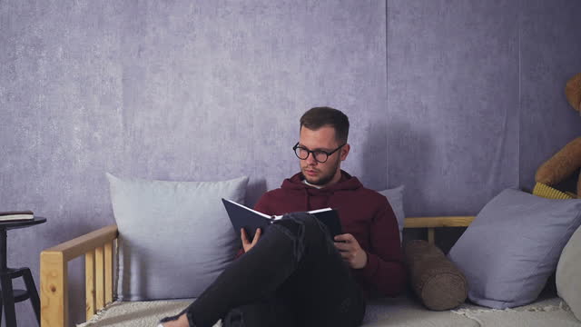 Male Student Delving into Book in Comfortable Living Space