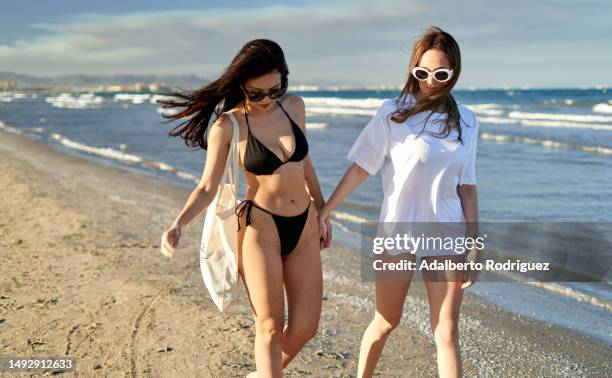 photo of two women enjoying a romantic stroll along the beach - civil partnership stock pictures, royalty-free photos & images