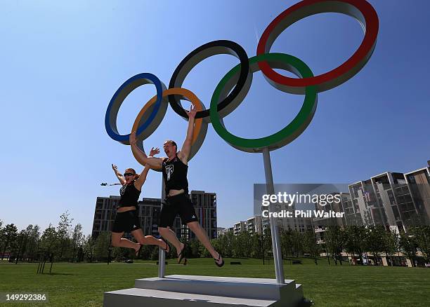 Jason Koster and Moira De Villiers of New Zealand leap in front of the Olympic rings inside the Olympic Village ahead of the London 2012 Olympic...