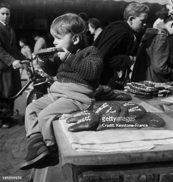 Enfant dans un stand de cochons en pain d'épice à la foire du Trône à Paris, le 9 avril 1955.