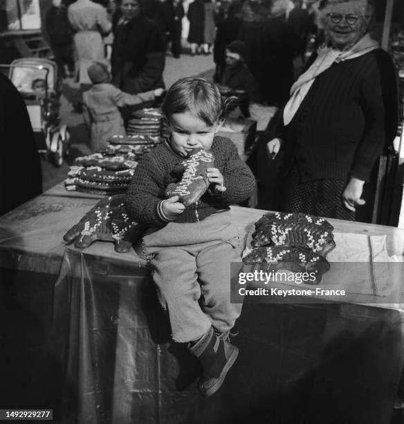 Enfant dans un stand de cochons en pain d'épice à la foire du Trône à Paris, le 9 avril 1955.