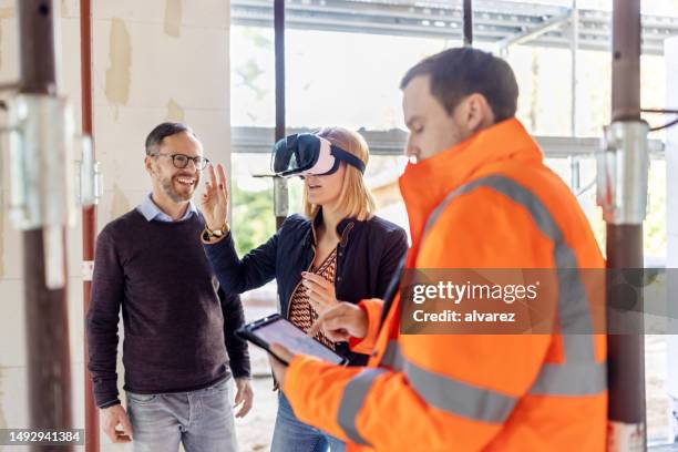 engineer showing construction design to a couple on virtual reality glasses at building site - site stock pictures, royalty-free photos & images