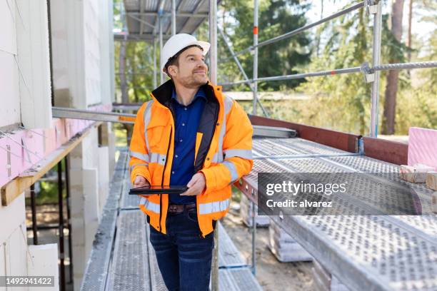 bauingenieur mit digitalem tablet bei der arbeit auf der baustelle - bauingenieur stock-fotos und bilder