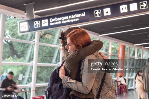 young woman embracing her friend on airport - gate imagens e fotografias de stock