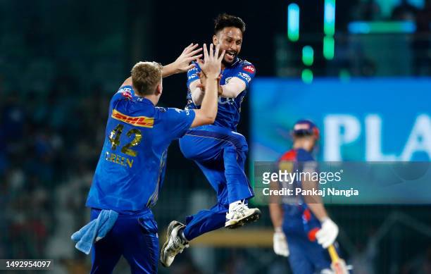 Akash Madhwal of Mumbai Indians celebrates with teammate Cameron Green after taking the wicket of Nicholas Pooran of Lucknow Super Giants during the...