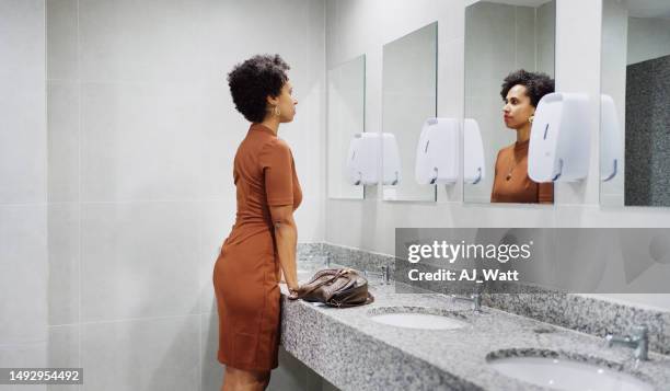 businesswoman mentally preparing for speech in a office bathroom - woman in bathroom stock pictures, royalty-free photos & images