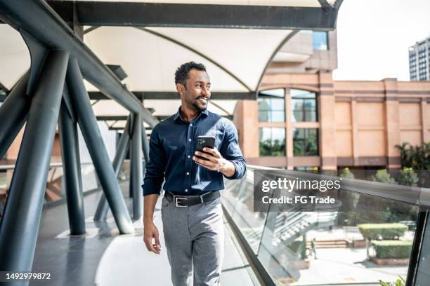 hombre de negocios mirando la vista mientras camina por un puente peatonal - mirar alrededor fotografías e imágenes de stock
