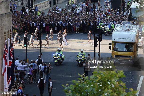 Crowds surround a torchbearer carrying the Olympic flame along Whitehall towards Parliament Square during Day 69 of the London 2012 Olympic Torch...