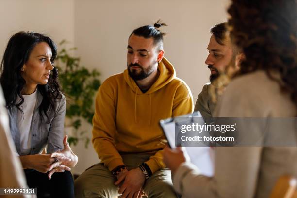 anxious young woman sharing her struggles with her peers during a group therapy session - beroende bildbanksfoton och bilder