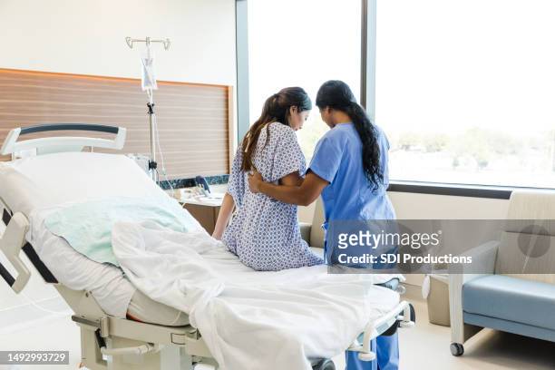 unrecognizable female nurse helps woman get out of hospital bed - patientkontakt bildbanksfoton och bilder