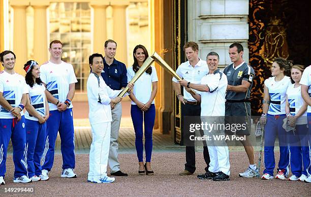 Prince William, Duke of Cambridge, Catherine, Duchess of Cambridge and Prince Harry watch Wai-Ming hand over the London 2012 Olympic Torch to John...