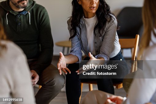 Anxious young woman sharing her struggles with her peers during a group therapy session Anxious young woman sharing her struggles with her peers during a group therapy session