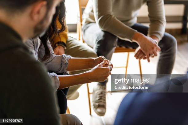 personas que ansiosamente mueven sus manos mientras comparten historias durante una sesión de terapia grupal - terapia de grupo fotografías e imágenes de stock