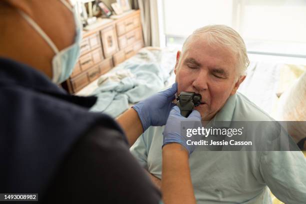 care worker wearing medical face mask shaving  face of senior man with dementia - kind face stock pictures, royalty-free photos & images