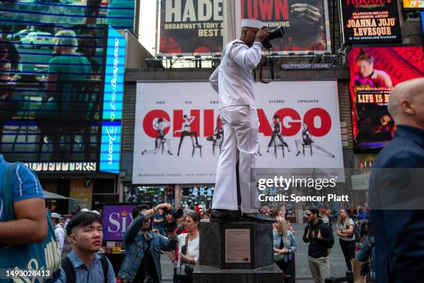 Sailor takes a picture from a flag pole in Times Square during the start of the 35th annual Fleet Week on May 24, 2023 in New York City. Nine ships,...