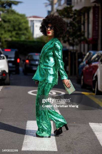 Elton Ilirjani wears green shiny sequined suit, sunglasses & bag Philipp Plein during the 76th Cannes film festival on May 24, 2023 in Cannes, France.