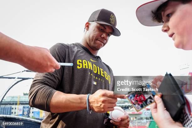 Juan Soto of the San Diego Padres signs autographs for fans before the game against the Washington Nationals at Nationals Park on May 24, 2023 in...