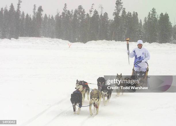 Torchbearer Janet Whitesell carries the Olympic Flame on a dogsled during the 2002 Salt Lake Olympic Torch Relay in Gallatin County Montana, near...
