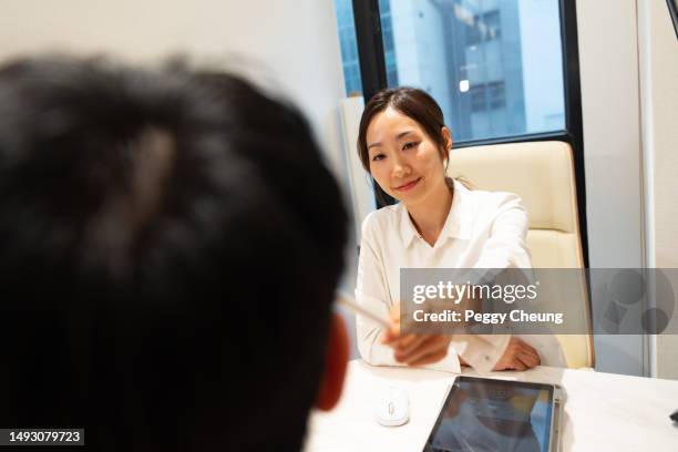 an asian female beauty consultant / aesthetic doctor is having a consultation session with an asian male client. - consultation lake stock pictures, royalty-free photos & images