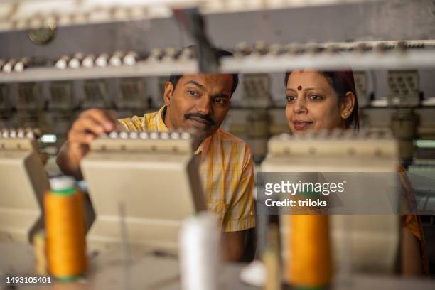 focused workers holding threads in spools manufacturing machinery in factory - textile mill stock pictures, royalty-free photos & images