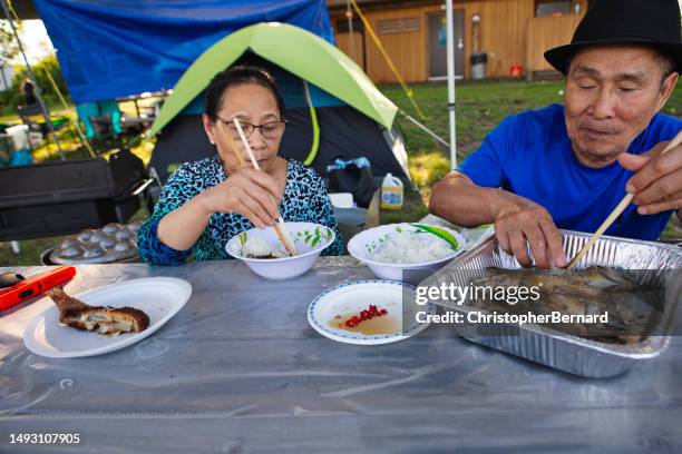 couple eating fish rice meal siitting outside. - regnbågsforell bildbanksfoton och bilder