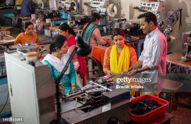 manager showing sample of printed fabric to female workers at factory - textile printing stock pictures, royalty-free photos & images