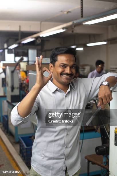 glücklicher manager, der in der textilfabrik ein ok-zeichen an der ausrüstung zeigt - ok werk stock-fotos und bilder