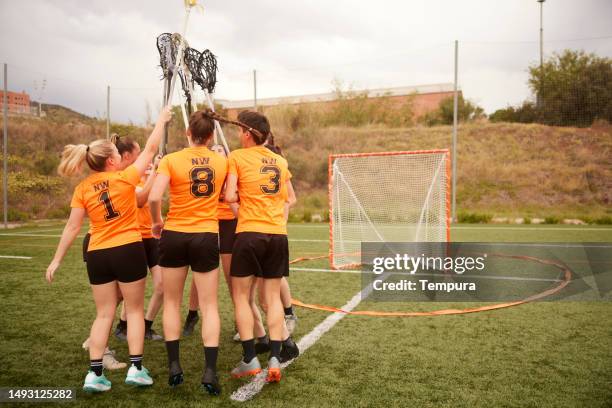 euphoric lacrosse players celebrate win with raised sticks - lacrosse stick stock pictures, royalty-free photos & images