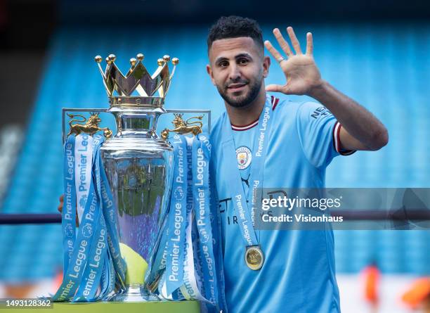 Riyad Mahrez of Manchester City holds up five fingers to indicate the five Premier League trophies he's won as a player after during the Premier...