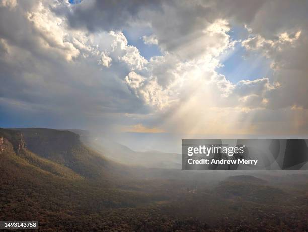 sunbeam rain clouds in valley, blue mountains - blue mountain stock pictures, royalty-free photos & images