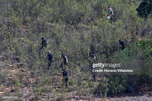 Police investigators use shovels while walking through the search area at the beginning of the 3rd day of the search for remains of Madeleine McCann...