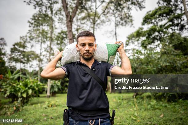 mature agricultor man carrying a bag  on his back at farm - agricultor stock pictures, royalty-free photos & images