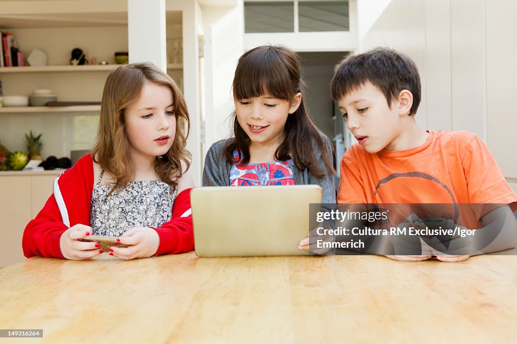 Children using tablet computer at table