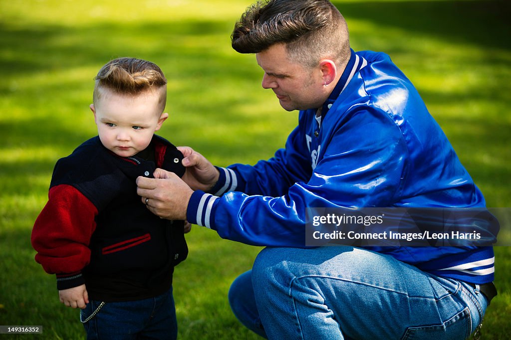 Man buttoning sons jacket