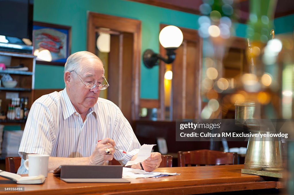 Older man using tablet computer in cafe