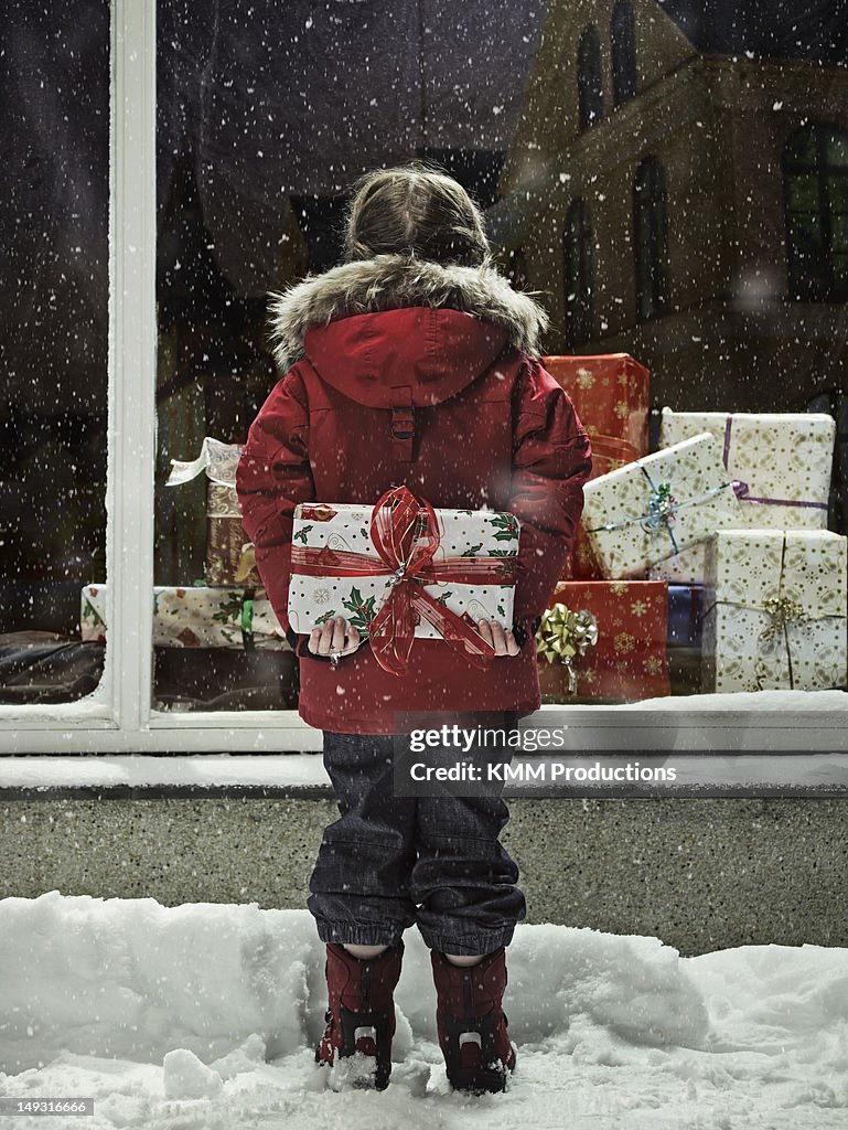 Girl holding Christmas present in snow