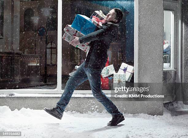 man carrying christmas gifts in snow - man snow stock pictures, royalty-free photos & images