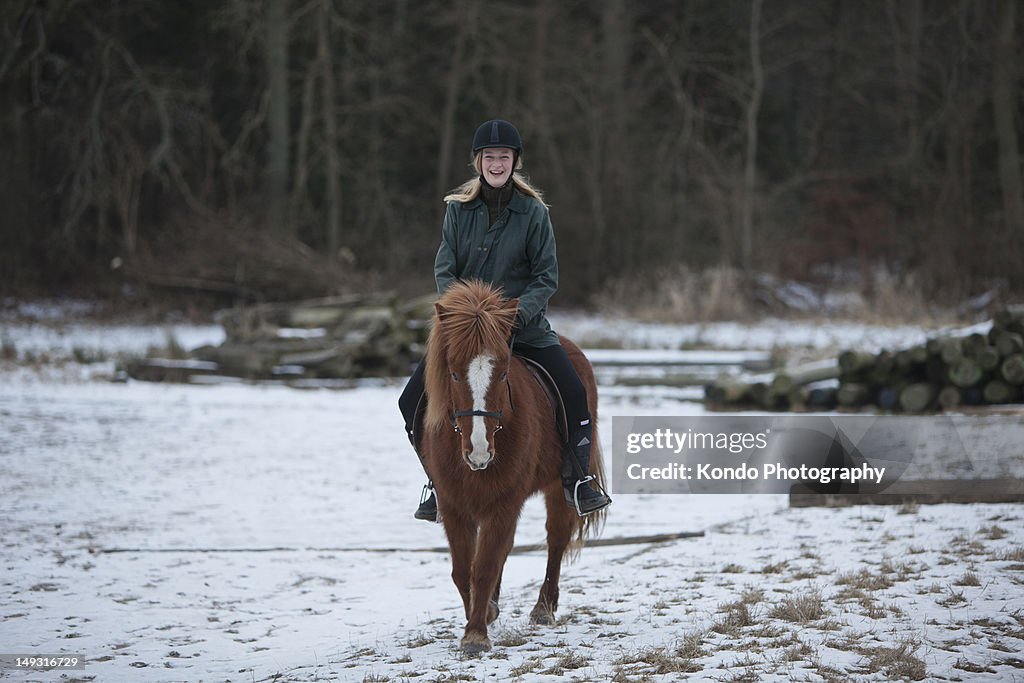 Woman riding horse in snow