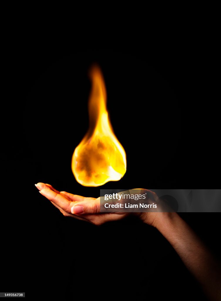 Hand holding burning flame