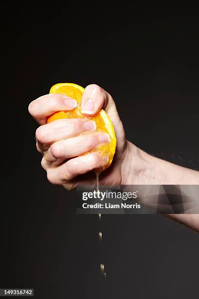 hand squeezing orange - estrujar fotografías e imágenes de stock