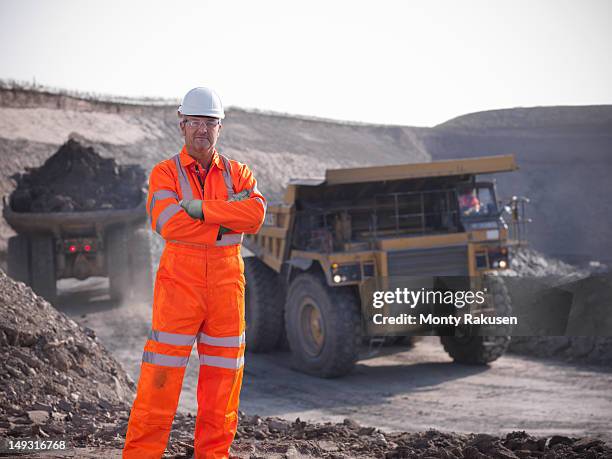 portrait of coalminer with coal trucks in the background - mining worker stock pictures, royalty-free photos & images