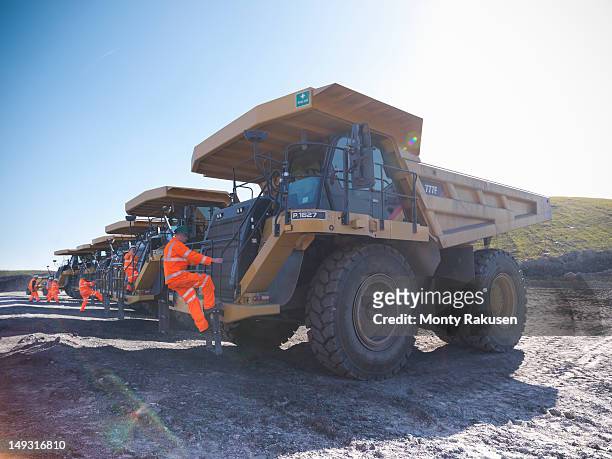 dumper truck drivers climbing aboard trucks in opencast coalmine - trucks in a row stock pictures, royalty-free photos & images