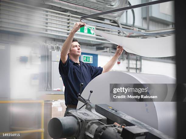 printer feeding paper into press in printworks - menschliche tätigkeit stock-fotos und bilder