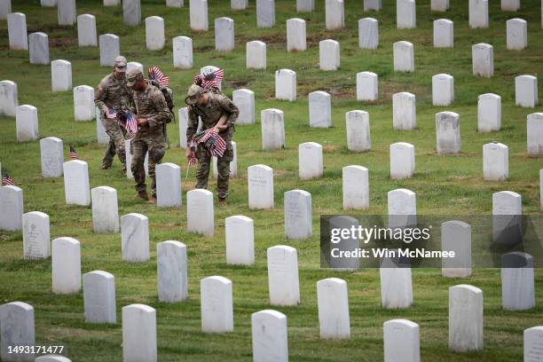 Members of the 3rd U.S. Infantry Regiment place flags at the headstones of U.S. Military personnel buried at Arlington National Cemetery, in...